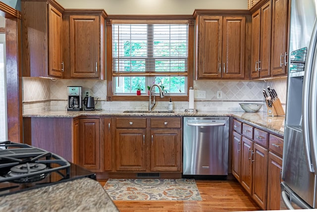 280 Center Rd, Ozark, MO 65721 - kitchen featuring appliances with stainless steel finishes, light wood finished floors, brown cabinetry, and decorative backsplash