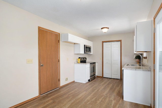904 N 41st St, Nixa, MO 65714 - kitchen with appliances with stainless steel finishes, light wood-type flooring, and white cabinets
