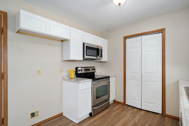 904 N 41st St, Nixa, MO 65714 - kitchen with stainless steel appliances, wood finished floors, white cabinetry, and light countertops