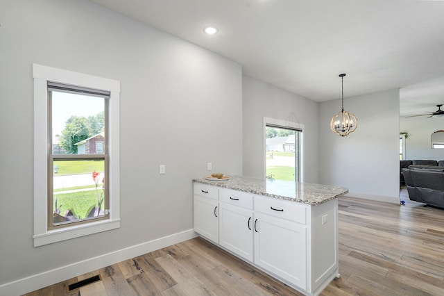 1240 E Keeling Pl, Bolivar, MO 65613 - kitchen featuring a peninsula, white cabinets, light stone counters, open floor plan, and light wood-style flooring