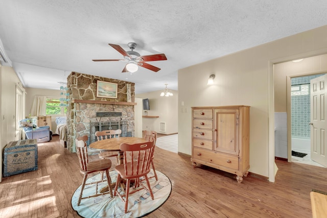 3637 State Highway Y, Forsyth, MO 65653 - dining room featuring a ceiling fan, wood finished floors, a textured ceiling, a fireplace, and a chandelier