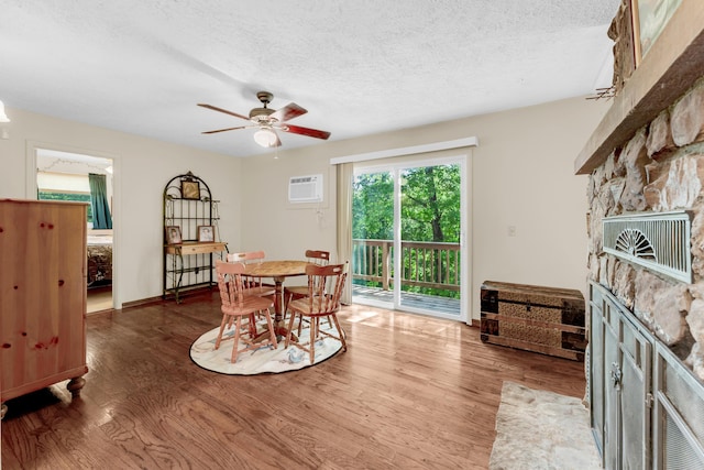 3637 State Highway Y, Forsyth, MO 65653 - dining room with a stone fireplace, wood finished floors, a textured ceiling, ceiling fan, and a wall unit AC