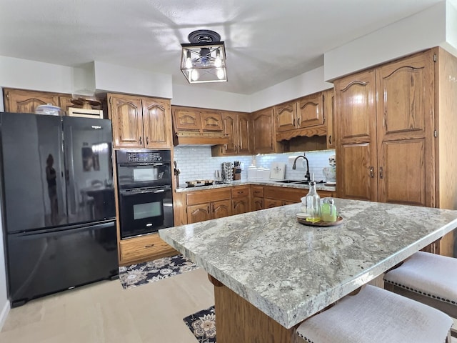 18189 2nd St, Eminence, MO 65466 - kitchen featuring black appliances, brown cabinets, decorative backsplash, under cabinet range hood, and a breakfast bar