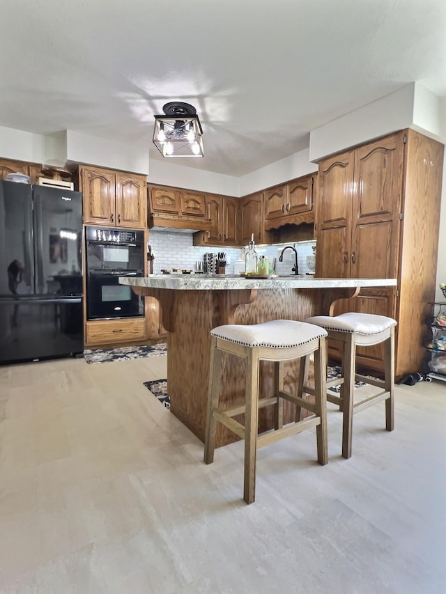 18189 2nd St, Eminence, MO 65466 - kitchen featuring black appliances, a breakfast bar, decorative backsplash, and light countertops