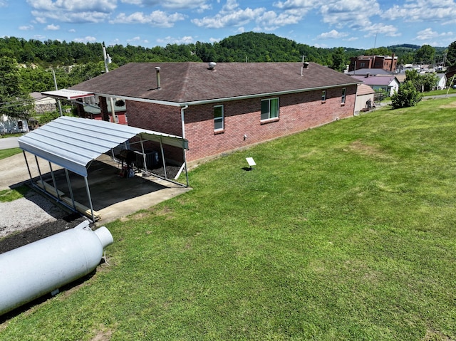 18189 2nd St, Eminence, MO 65466 - back of house featuring brick siding, a lawn, a shingled roof, a detached carport, and driveway