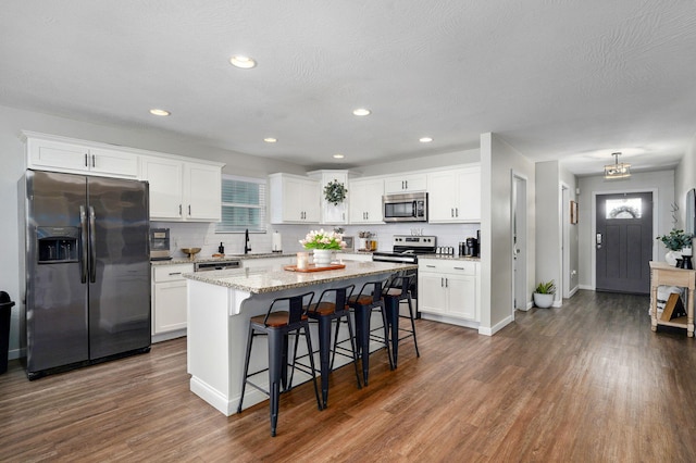 504 Gauge St, Willard, MO 65781 - kitchen featuring stainless steel appliances, a breakfast bar area, decorative backsplash, dark wood-style flooring, and recessed lighting