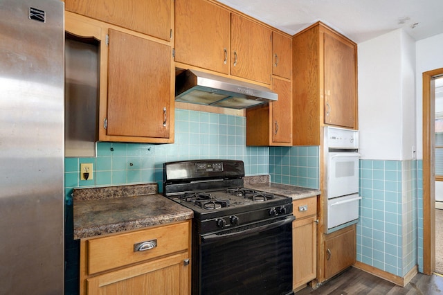 304 N Main St, Lockwood, MO 65682 - kitchen with gas stove, under cabinet range hood, white oven, a warming drawer, and dark wood-type flooring
