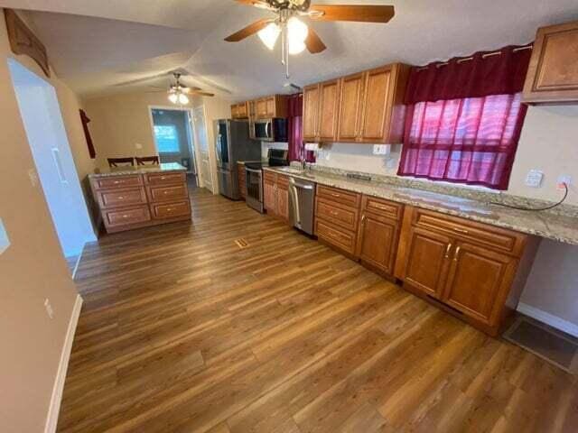203 Forest Park Ln, Branson, MO 65616 - kitchen featuring stainless steel appliances, brown cabinetry, wood finished floors, ceiling fan, and lofted ceiling