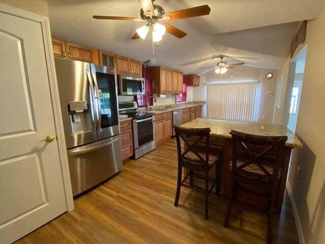 203 Forest Park Ln, Branson, MO 65616 - kitchen with stainless steel appliances, brown cabinets, wood finished floors, ceiling fan, and lofted ceiling