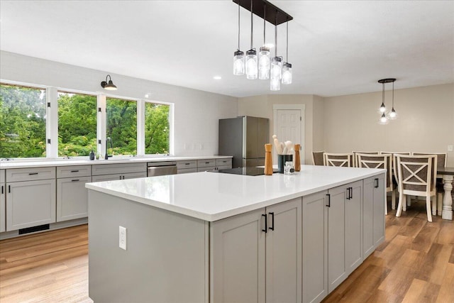 103 W Secluded Ln, Nixa, MO 65714 - kitchen with stainless steel appliances, light countertops, light wood-type flooring, decorative light fixtures, and recessed lighting