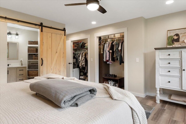 103 W Secluded Ln, Nixa, MO 65714 - bedroom featuring wood finished floors, a barn door, multiple closets, recessed lighting, and ensuite bath