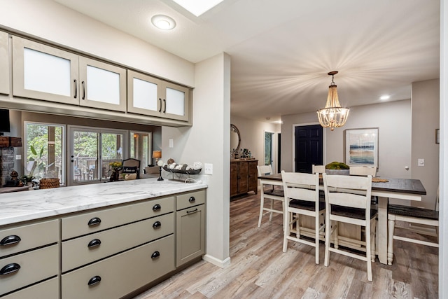 348 Sunset Cv Unit 413, Branson, MO 65616 - kitchen featuring gray cabinets, a chandelier, light wood-style floors, light stone counters, and decorative light fixtures