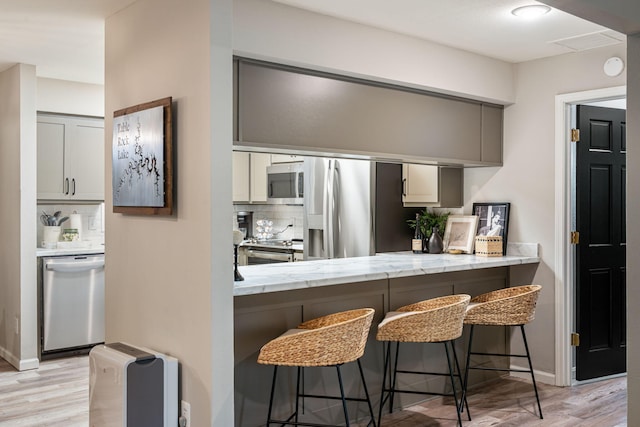 348 Sunset Cv Unit 413, Branson, MO 65616 - kitchen featuring appliances with stainless steel finishes, light wood-type flooring, a kitchen breakfast bar, and backsplash