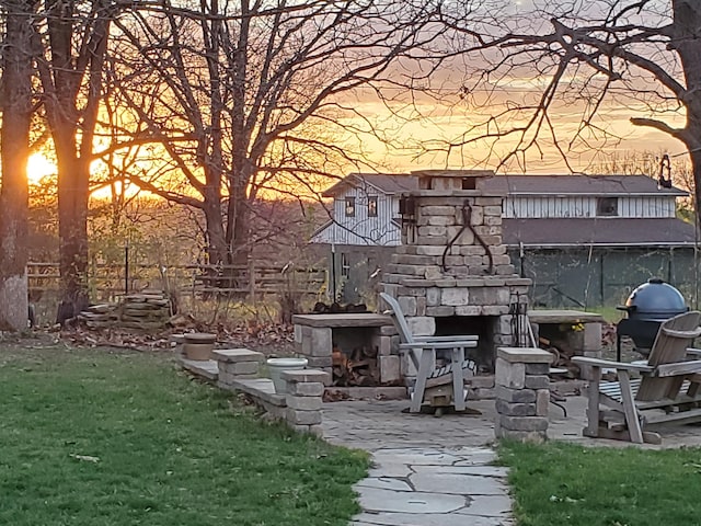 1179 N Pine St, Marshfield, MO 65706 - patio terrace at dusk featuring a fireplace and area for grilling