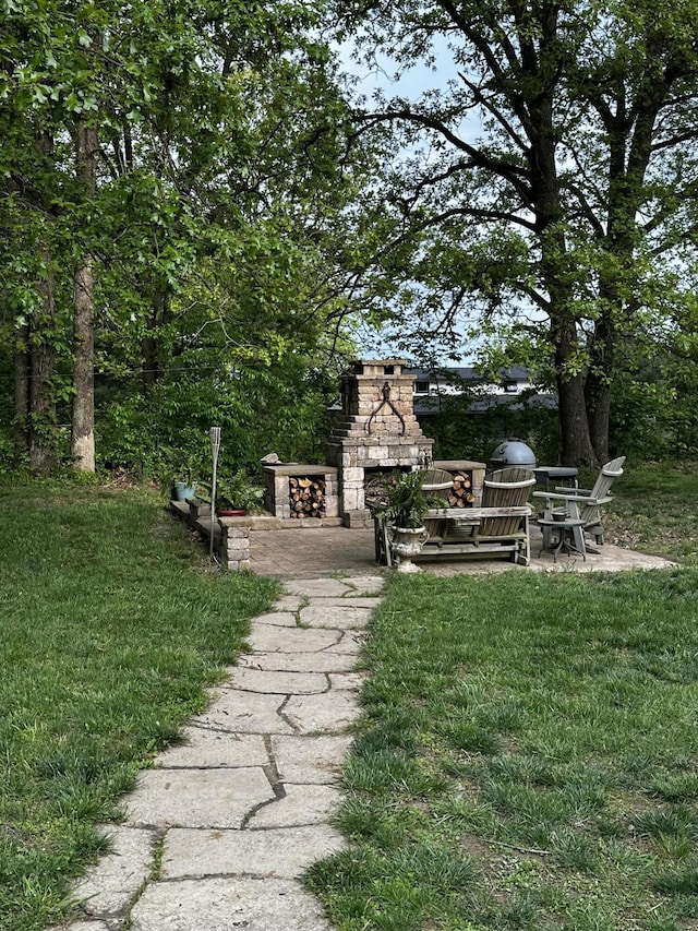 1179 N Pine St, Marshfield, MO 65706 - view of green lawn featuring an outdoor stone fireplace and a patio area