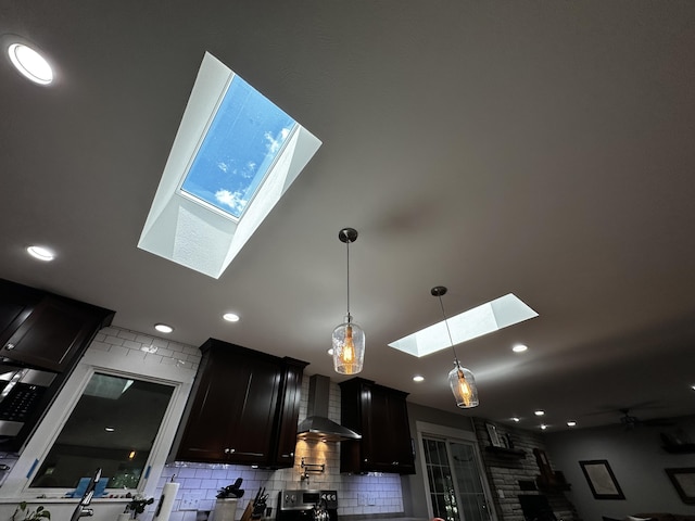 1179 N Pine St, Marshfield, MO 65706 - detailed view of a skylight, wall chimney exhaust hood, backsplash, dark cabinets, and hanging light fixtures