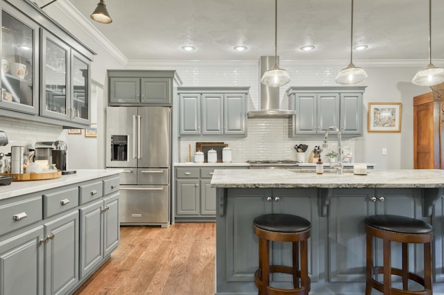1251 S Rosemoor Dr, Nixa, MO 65714 - kitchen with high end fridge, gray cabinets, wall chimney exhaust hood, a kitchen breakfast bar, and decorative backsplash