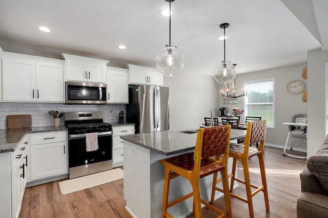 816 S Rockburn Ct, Nixa, MO 65714 - kitchen with appliances with stainless steel finishes, tasteful backsplash, light wood-style flooring, white cabinets, and a breakfast bar
