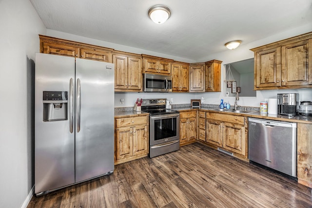 701 Lexington Cir, Clever, MO 65631 - kitchen with stainless steel appliances, brown cabinetry, dark wood-style floors, and dark countertops