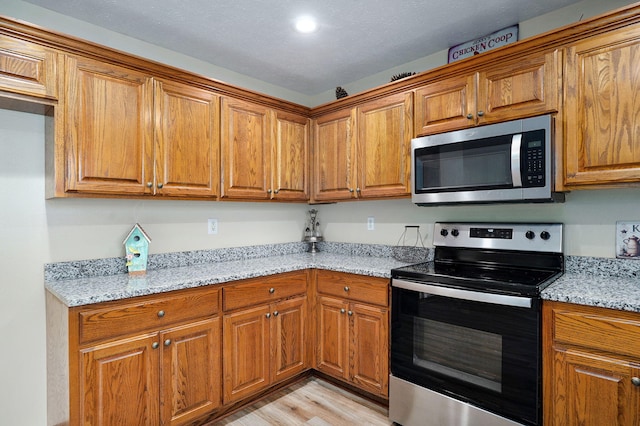 431 S Yellowwood Dr, Springfield, MO 65809 - kitchen featuring stainless steel appliances, brown cabinets, light wood finished floors, light stone counters, and recessed lighting