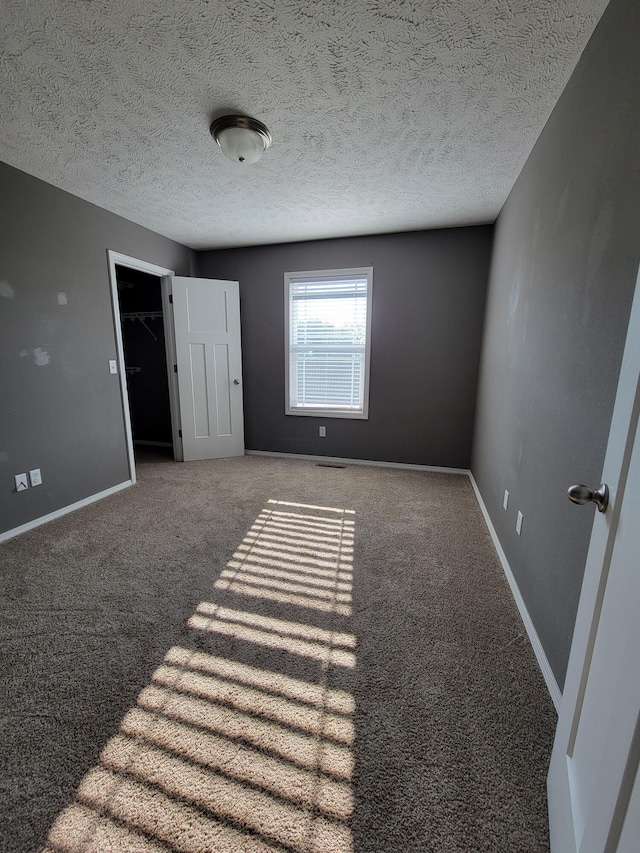 100 Hawthorn Ave, Rogersville, MO 65742 - unfurnished bedroom with carpet flooring, a textured ceiling, and a walk in closet