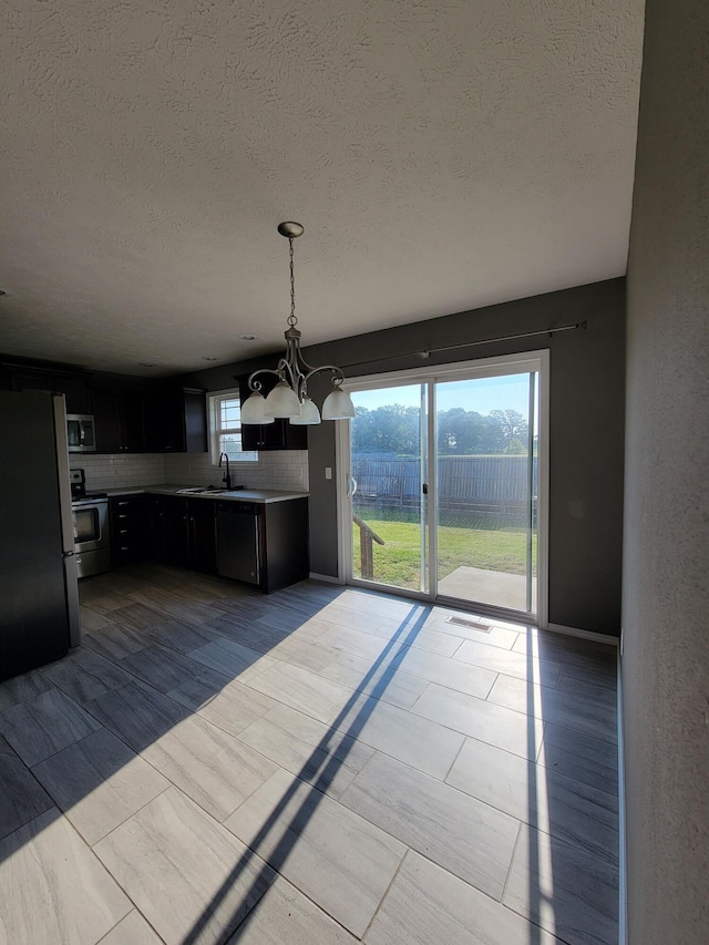 100 Hawthorn Ave, Rogersville, MO 65742 - kitchen with appliances with stainless steel finishes, a chandelier, decorative backsplash, a textured ceiling, and dark cabinetry