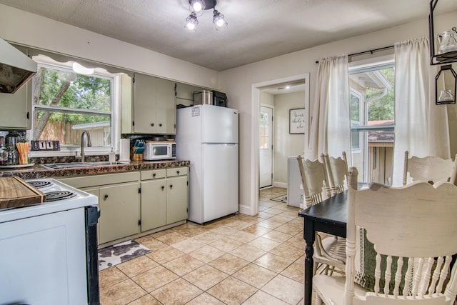 135 Roark Ave, Branson, MO 65616 - kitchen featuring white appliances, dark countertops, healthy amount of natural light, and light tile patterned flooring