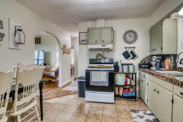 135 Roark Ave, Branson, MO 65616 - kitchen featuring electric range oven, under cabinet range hood, arched walkways, dark countertops, and light tile patterned floors