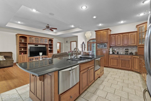 318 Fox Fire Ct, Joplin, MO 64801 - kitchen featuring stainless steel appliances, open floor plan, an island with sink, a ceiling fan, and brown cabinets