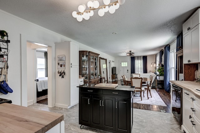 1508 S Moffet Ave, Joplin, MO 64804 - kitchen with healthy amount of natural light, dark cabinetry, a kitchen island, a textured ceiling, and white cabinets