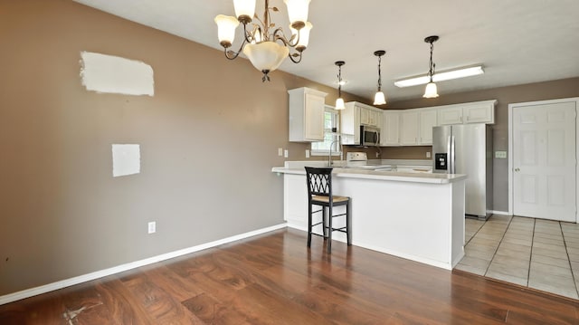 205 W Hunter Dr, Nixa, MO 65714 - kitchen with appliances with stainless steel finishes, a peninsula, a chandelier, wood finished floors, and light countertops