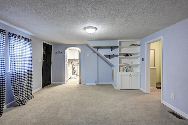 1027 S Orner St, Carthage, MO 64836 - unfurnished bedroom with light colored carpet, arched walkways, connected bathroom, and a textured ceiling