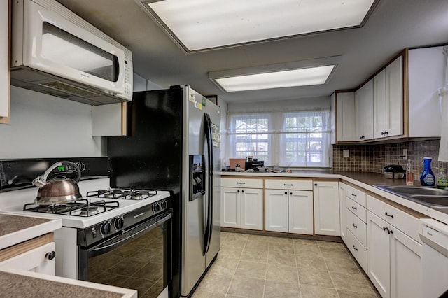 1027 S Orner St, Carthage, MO 64836 - kitchen with white appliances, decorative backsplash, white cabinets, and light tile patterned floors