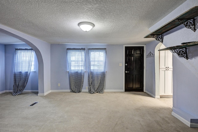 1027 S Orner St, Carthage, MO 64836 - foyer entrance featuring arched walkways, light carpet, plenty of natural light, and a textured ceiling