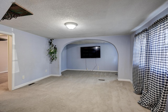 1027 S Orner St, Carthage, MO 64836 - unfurnished living room with arched walkways, carpet floors, and a textured ceiling