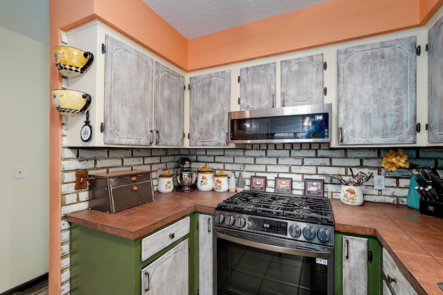 1648 N Yates Ave, Springfield, MO 65803 - kitchen with stainless steel appliances, tile countertops, a textured ceiling, and decorative backsplash
