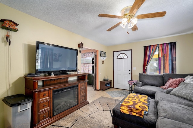 1648 N Yates Ave, Springfield, MO 65803 - living room featuring healthy amount of natural light, a ceiling fan, a textured ceiling, light tile patterned floors, and a glass covered fireplace