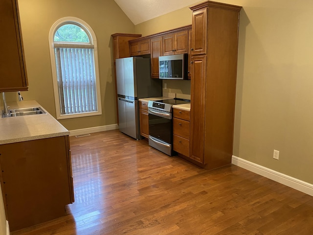 2114 E Finch St, Ozark, MO 65721 - kitchen with stainless steel appliances, wood finished floors, vaulted ceiling, light countertops, and brown cabinets