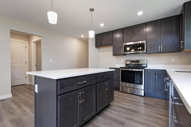 1851 N Patterson Ave, Springfield, MO 65803 - kitchen featuring appliances with stainless steel finishes, wood finished floors, decorative light fixtures, light countertops, and a center island