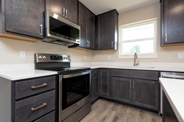 1851 N Patterson Ave, Springfield, MO 65803 - kitchen with appliances with stainless steel finishes, light wood-style flooring, dark brown cabinetry, and light countertops