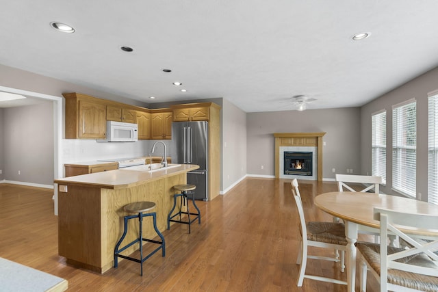 169 Tanner Rd, Branson, MO 65616 - kitchen featuring high end refrigerator, white microwave, ceiling fan, a fireplace, and a kitchen island with sink