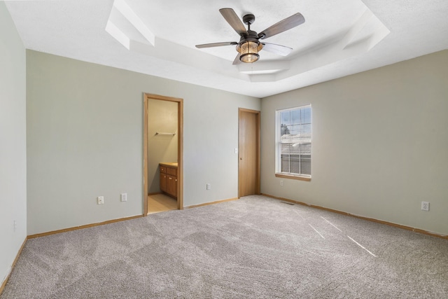 421 W White Ash Rd, Nixa, MO 65714 - unfurnished bedroom featuring a raised ceiling, light carpet, ensuite bath, and ceiling fan