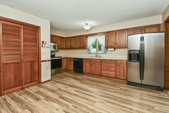 3642 N Olive Ct, Springfield, MO 65803 - kitchen featuring stainless steel appliances, light countertops, a textured ceiling, light wood-type flooring, and brown cabinetry