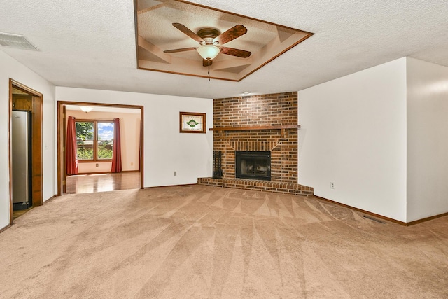 3642 N Olive Ct, Springfield, MO 65803 - unfurnished living room featuring a textured ceiling, a ceiling fan, carpet flooring, a brick fireplace, and a tray ceiling