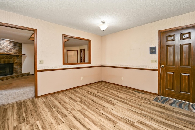 3642 N Olive Ct, Springfield, MO 65803 - unfurnished room with light wood finished floors, a fireplace, and a textured ceiling