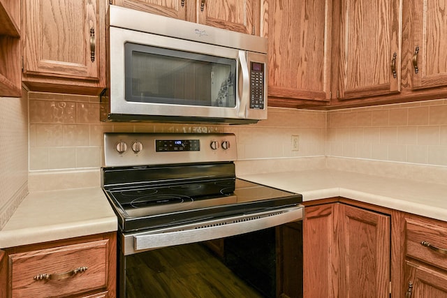 3642 N Olive Ct, Springfield, MO 65803 - kitchen with appliances with stainless steel finishes, tasteful backsplash, light countertops, and brown cabinetry