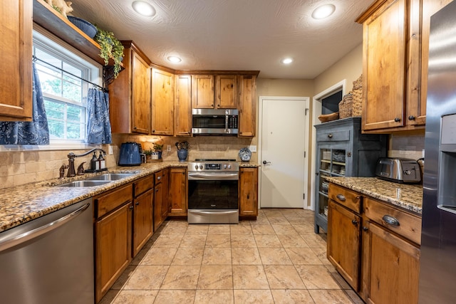 1021 W Whiteside St, Springfield, MO 65807 - kitchen with appliances with stainless steel finishes, decorative backsplash, brown cabinets, light stone countertops, and recessed lighting