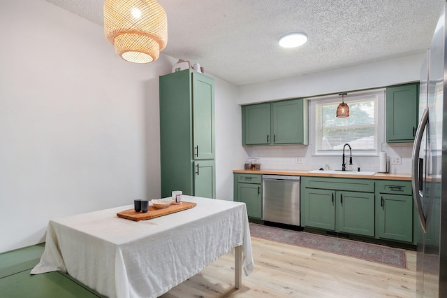 303 E Berkeley St, Springfield, MO 65807 - kitchen with green cabinetry, a textured ceiling, appliances with stainless steel finishes, tasteful backsplash, and light wood-style flooring