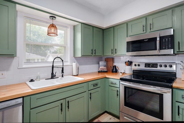 303 E Berkeley St, Springfield, MO 65807 - kitchen featuring green cabinetry, stainless steel appliances, wood counters, backsplash, and a textured ceiling