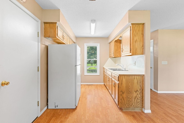 502 Sunrise St, Strafford, MO 65757 - kitchen with freestanding refrigerator, light wood finished floors, light countertops, and a textured ceiling